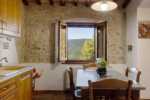 Una habitación con paredes de piedra, una mesa de comedor, sillas y un ventanal con vistas al paisaje.