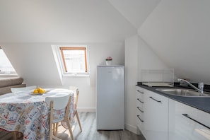 A compact kitchen with a refrigerator, sink, and dining area with a table and chairs.