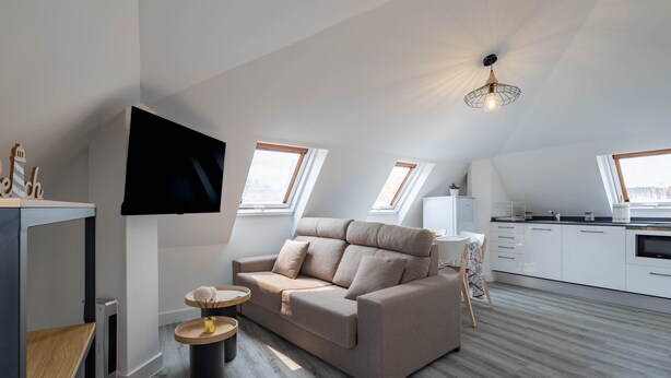 Un loft moderno con sofá, televisor, cocina y tragaluces.