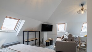 Un dormitorio moderno con cama, sofá, televisor y escritorio.