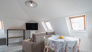 Un loft moderno con sofá, mesa de comedor y televisor.