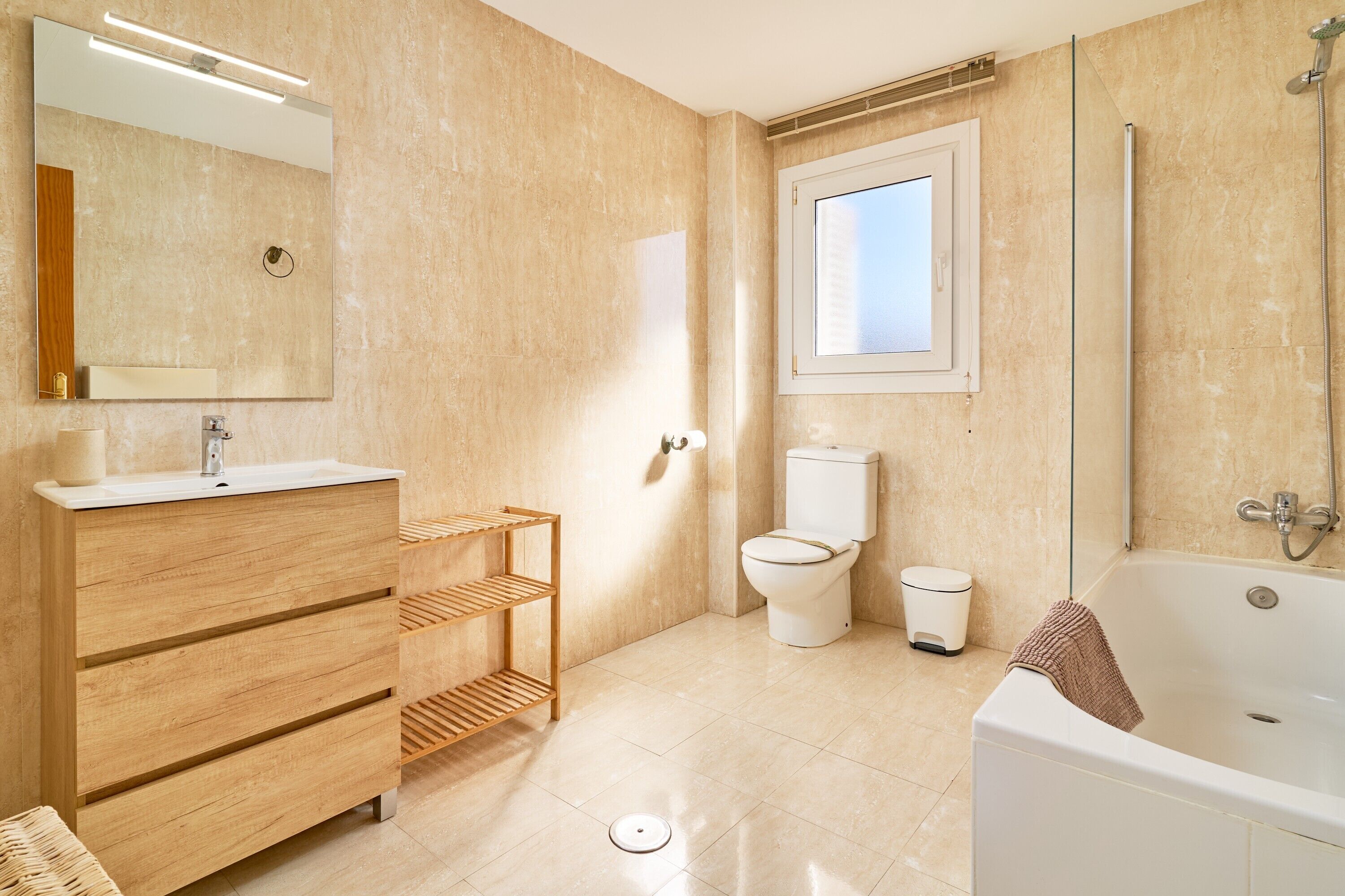 A modern bathroom with a wooden vanity, a toilet, a bathtub, and a shower.