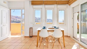 Un comedor con mesa y sillas, una ventana con vistas a las colinas y un ventanal corredero.