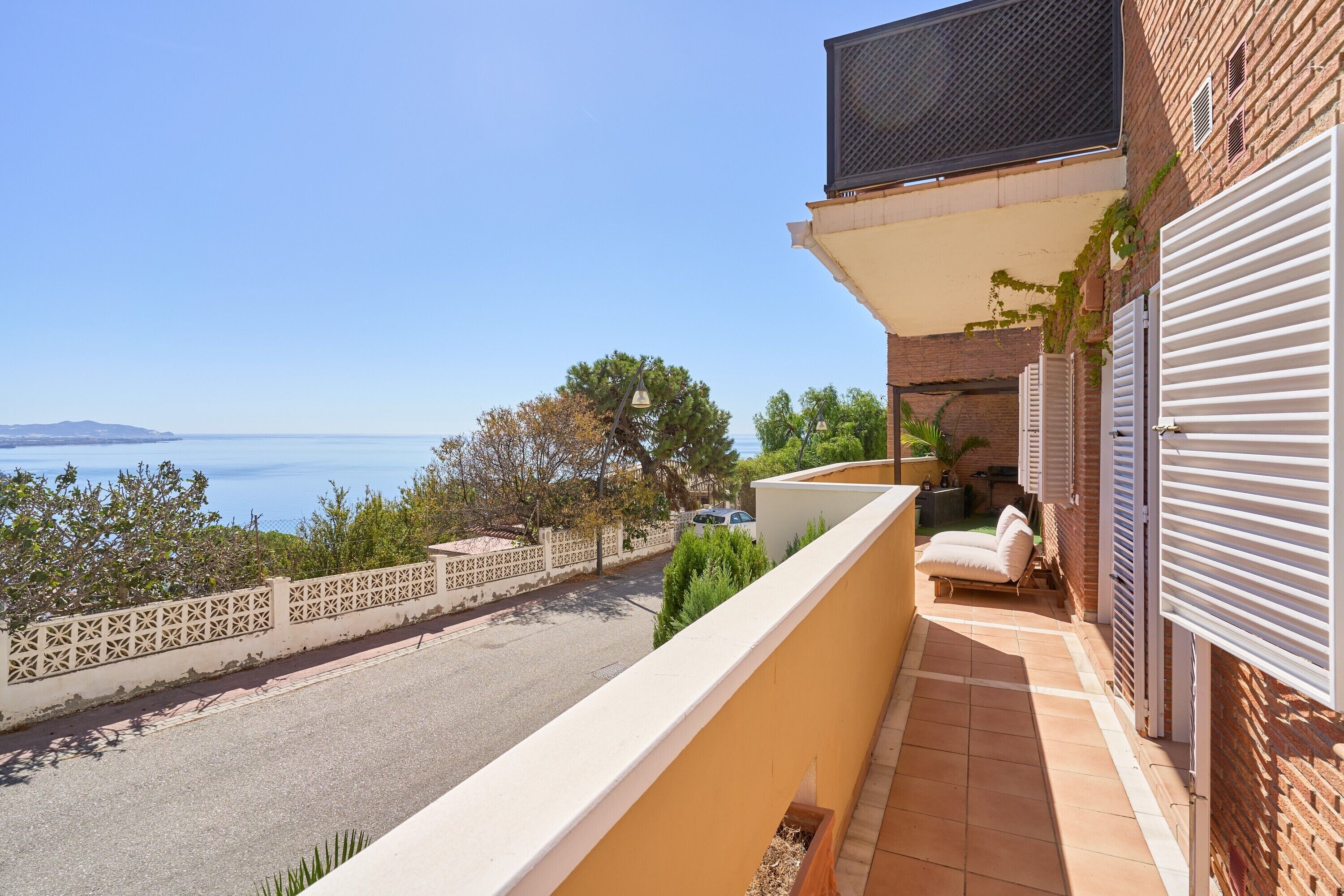 Ein Balkon mit Blick auf das Meer, ein Fliesenboden und ein Zierzaun.