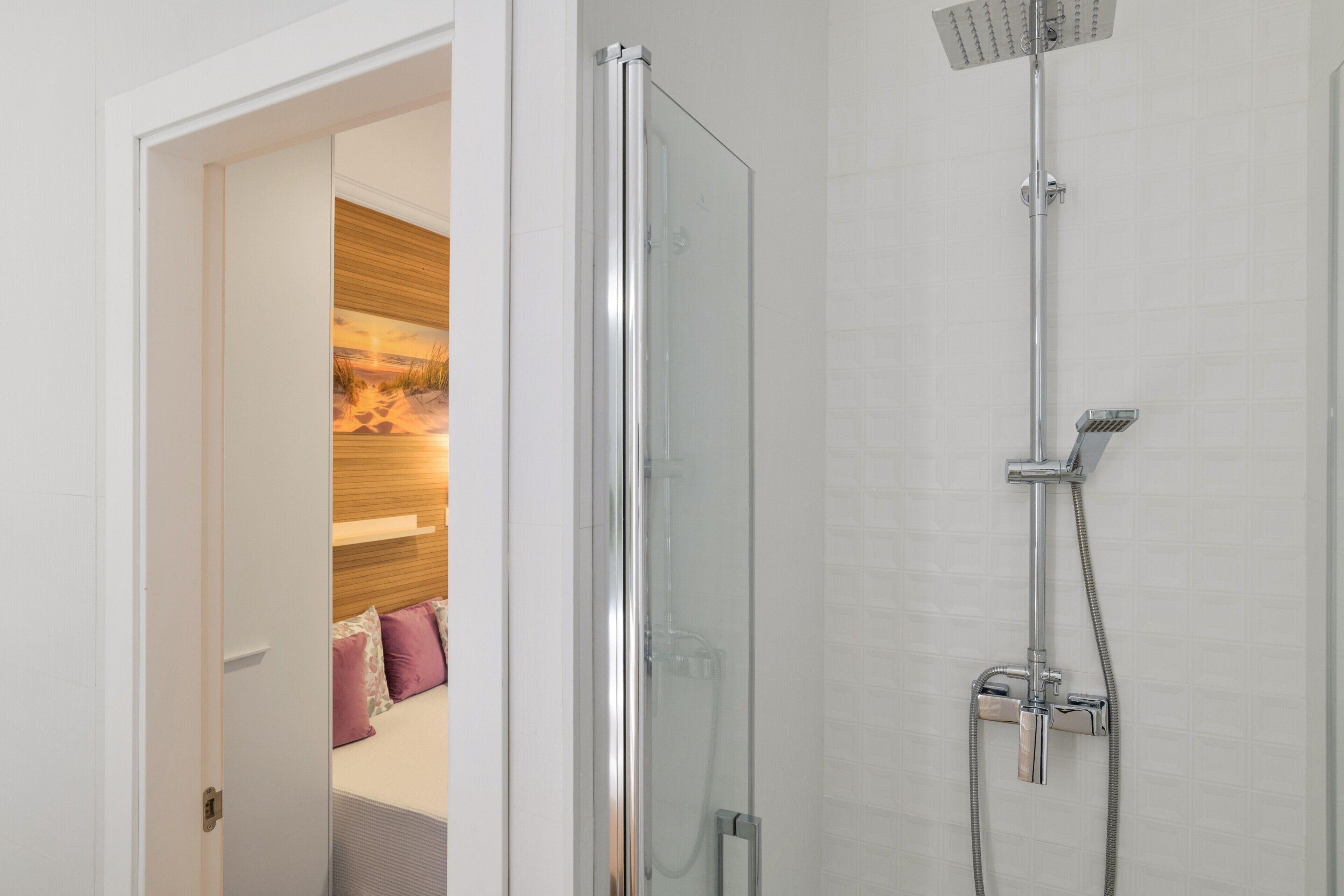 Een moderne badkamer met een douchecabine van glas, een handdouche en een wandmengkraan.