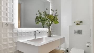 Een moderne badkamer met een wit wastafelmeubel, spiegel en toilet.