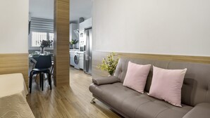 A modern living room with a sofa, a dining table with chairs, a kitchen area with appliances, and a window with blinds. - Apartment 'Reyes Católicos Conil' with Wi-Fi and Air Conditioning (Conil de la Frontera)