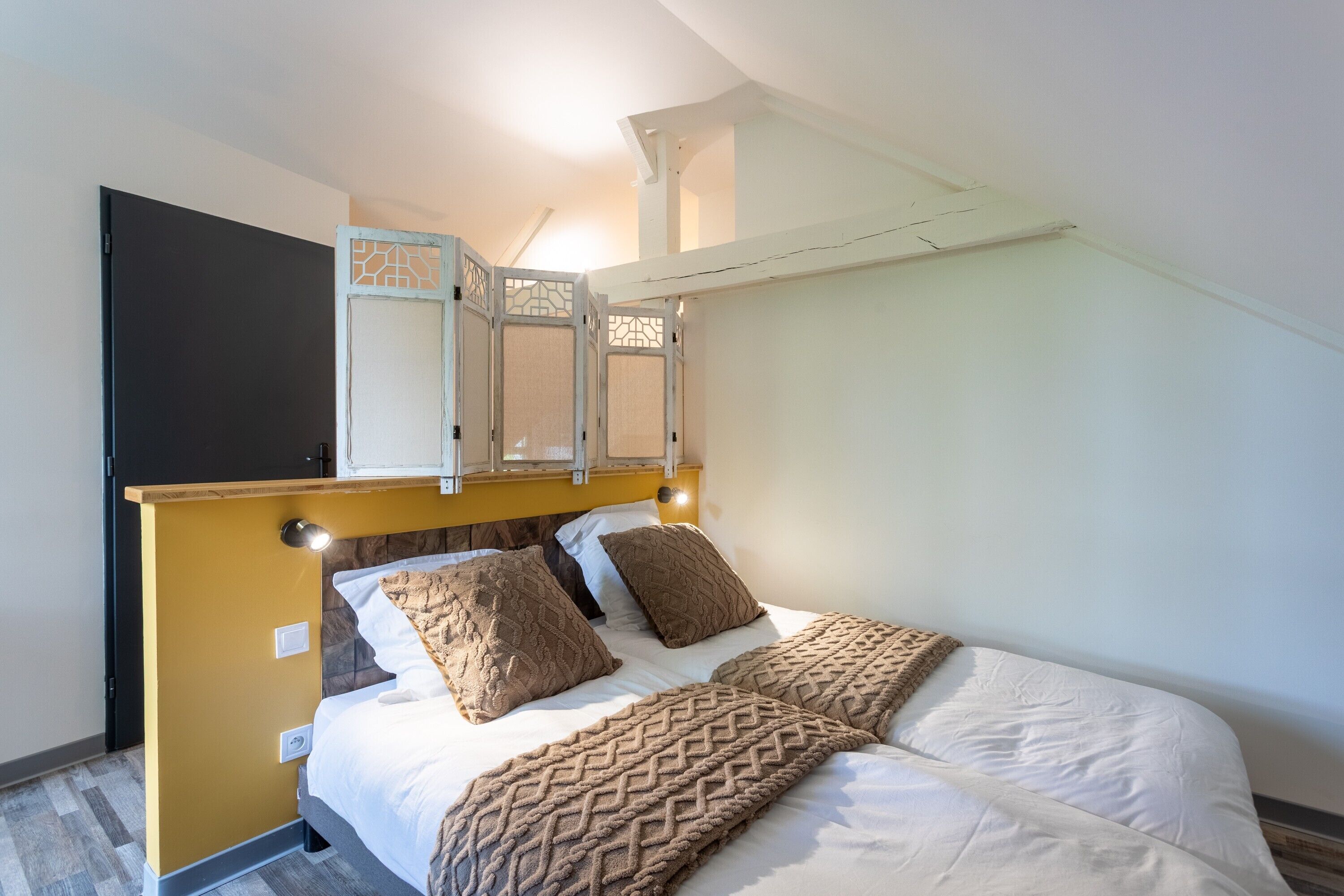 Ein Schlafzimmer mit Bett, Kopfteil, Tür und Deckenleuchte.