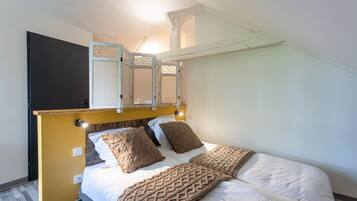 Ein Schlafzimmer mit Bett, Kopfteil, Tür und Deckenleuchte.