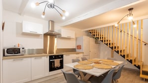 A modern kitchen with white cabinets, a stainless steel range hood, and a dining area with a table set for four.