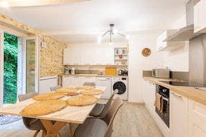 Una cucina moderna con un tavolo da pranzo per quattro persone, una lavatrice e un forno integrato.