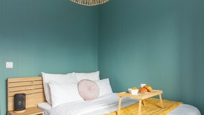 Une chambre à coucher avec un lit, une table de chevet, un plateau contenant des éléments pour le petit-déjeuner et un luminaire suspendu.