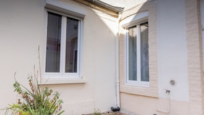 Un bâtiment doté d’une cour dallée, d’une plante en pot et d’une fenêtre.