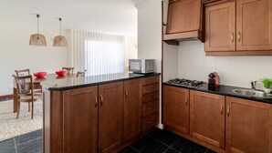 A modern kitchen with wooden cabinets, a central island, a gas stove, and pendant lighting.