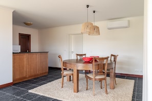 Un coin repas avec une table en bois, des chaises, un bol rouge et un luminaire suspendu.