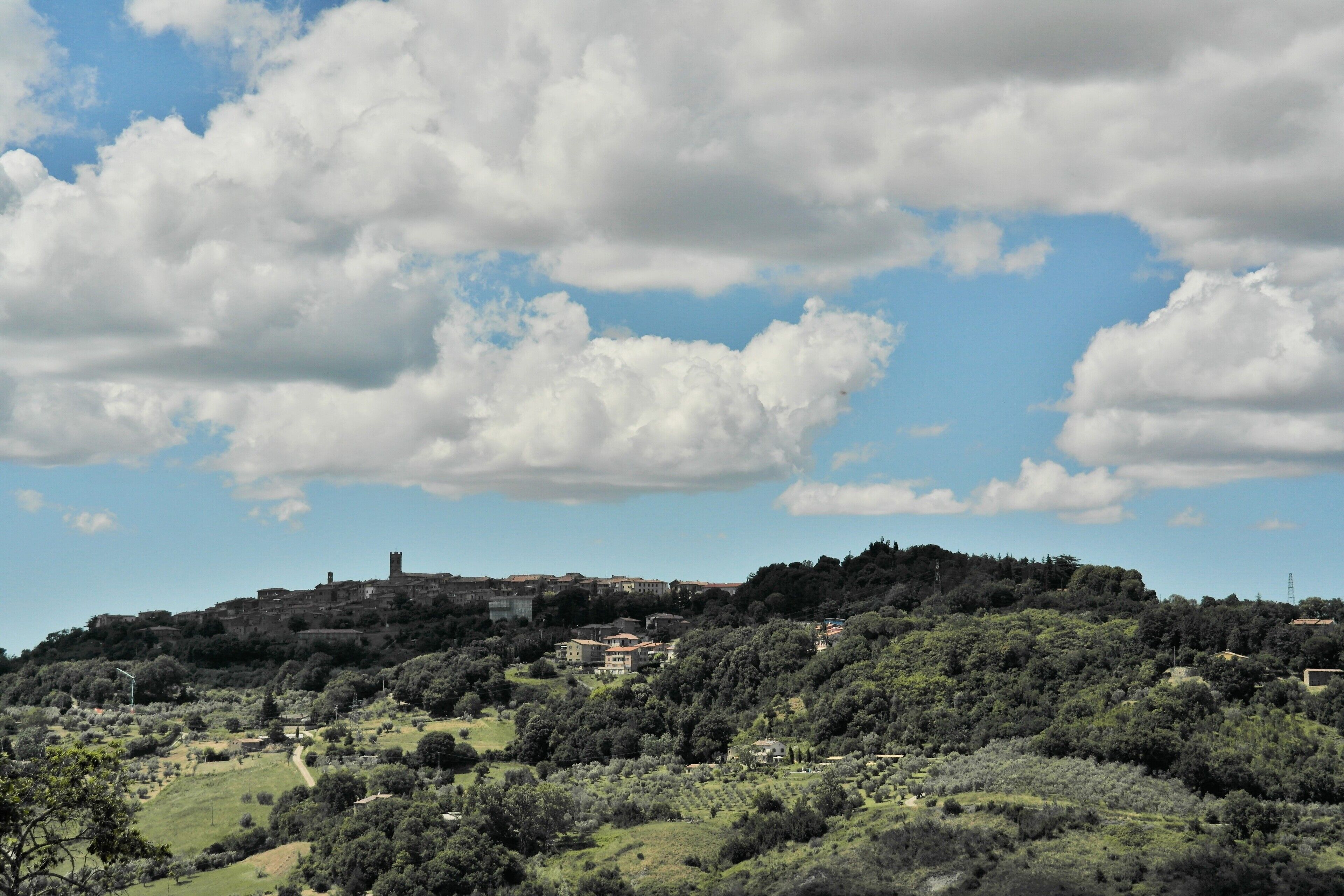 Une ville perchée sur une colline, dotée de bâtiments historiques, d’un château et d’une végétation luxuriante.