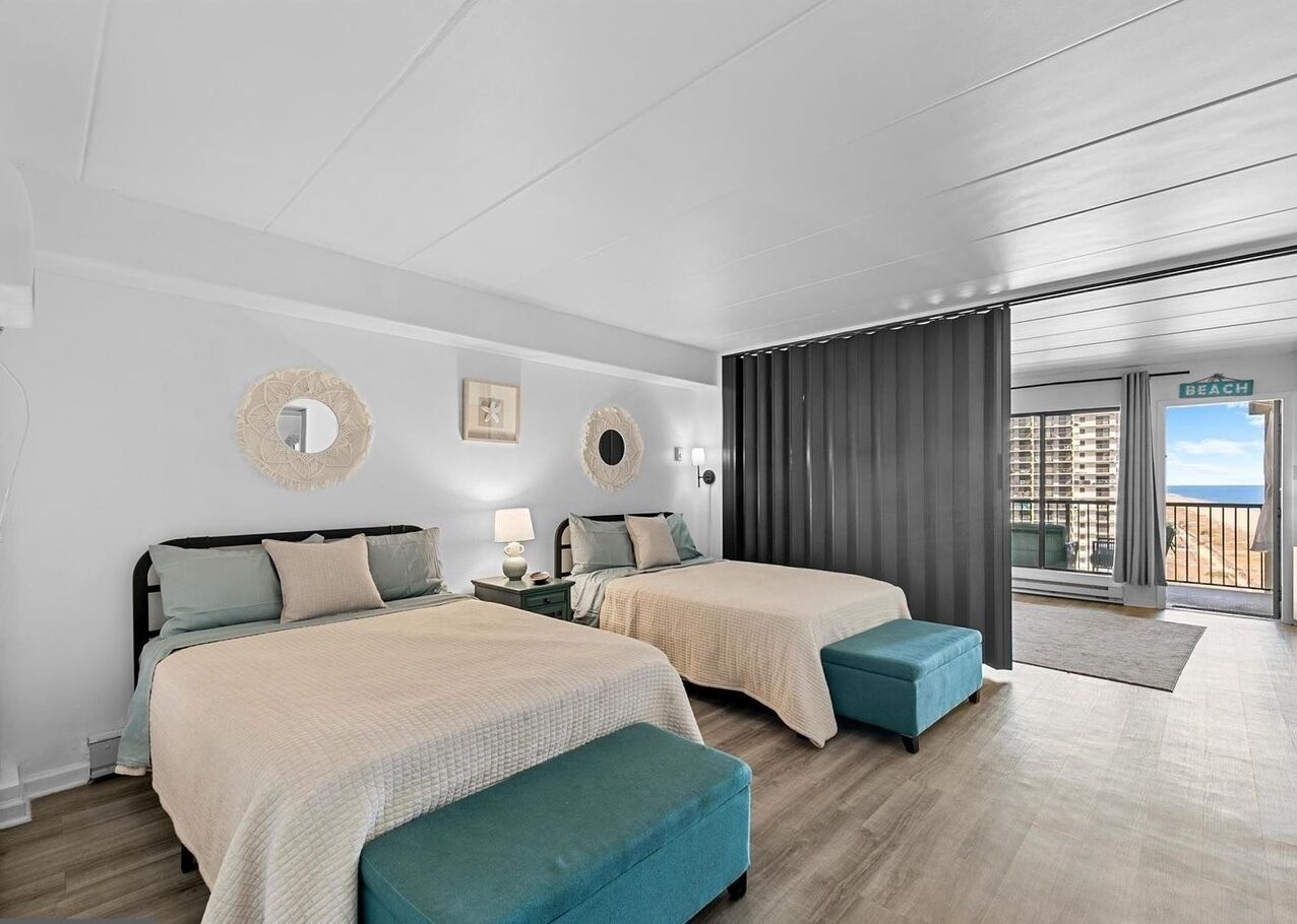 Ein Hotelzimmer mit zwei Betten, einem Balkon und Blick sowie einem großen Fenster.