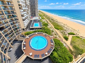 Een hotel met een zwembad op het dak, toegang tot het strand en uitzicht op de oceaan.