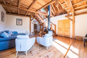 Ein geräumiger Wohnbereich mit hoher Holzbalkendecke, einer Treppe und einer großen Holztür.