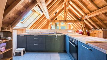 Een moderne keuken met dakraam, houten balken en uitzicht op de omgeving.