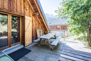 Une cabane en bois dotée d’une terrasse en bois, d’une table de pique-nique et d’une grande porte-fenêtre coulissante.