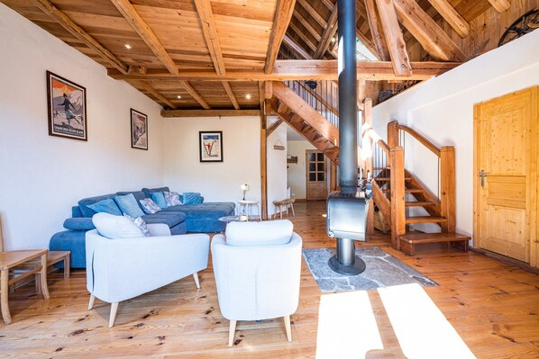 Un intérieur en bois comprenant un canapé, des fauteuils, une cheminée et un escalier.