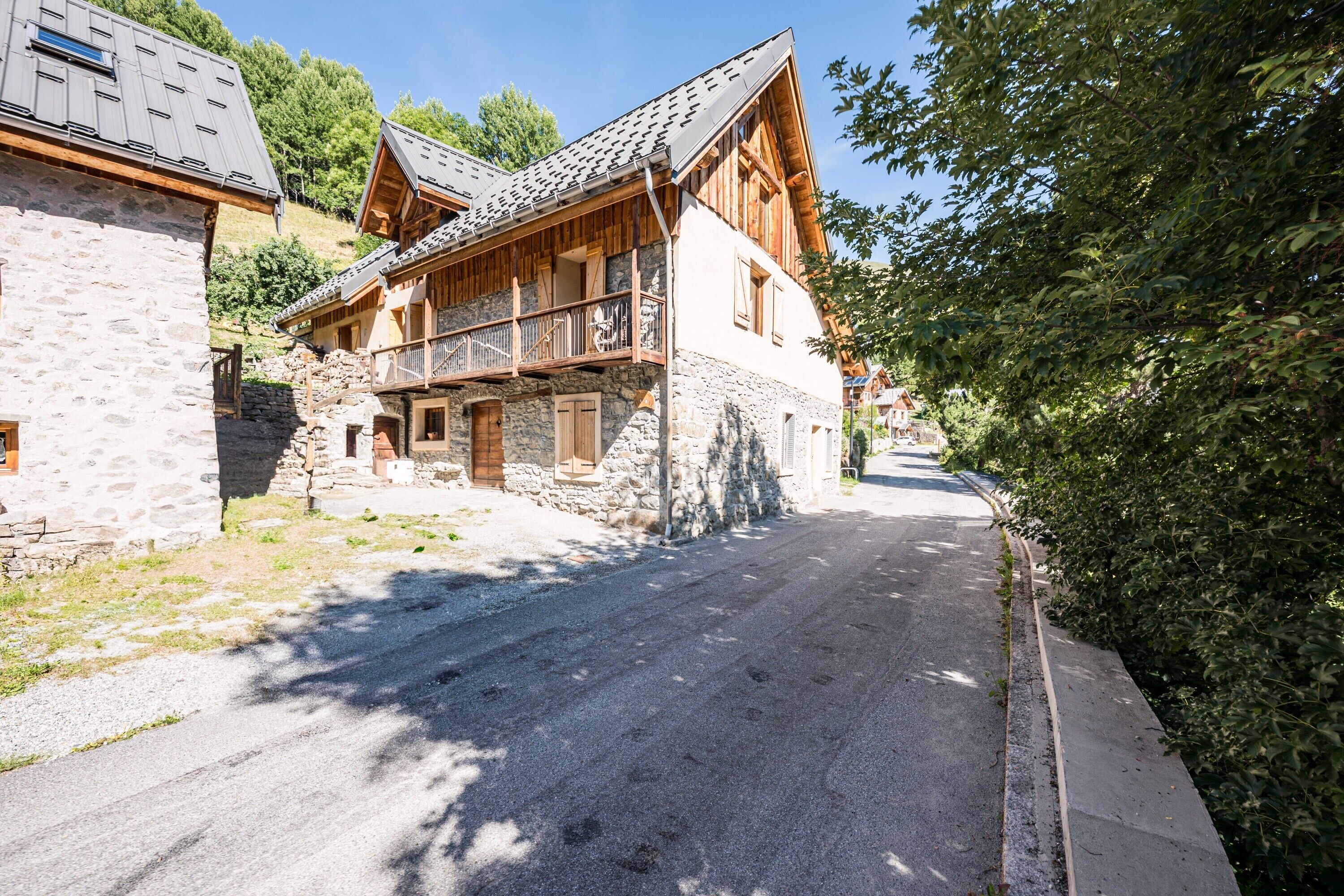 Un bâtiment de style chalet traditionnel, avec une façade en pierre, des balcons en bois et un ciel dégagé.