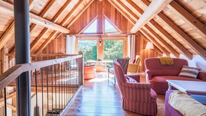 An attic-style room with wooden beams, a balcony, and a view of greenery outside. - Chalet 'La Grange Des Flocons' with Mountain View, Private Terrace and Private Garden (Valloire)