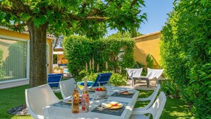 Un'area pranzo all'aperto con tavolo, sedie e una bottiglia di vino.