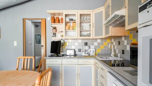 Una cucina compatta con tavolo, sedie, pensili, forno a microonde e macchina del caffè.