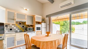 Una cucina con tavolo e sedie, forno, microonde e pensili.