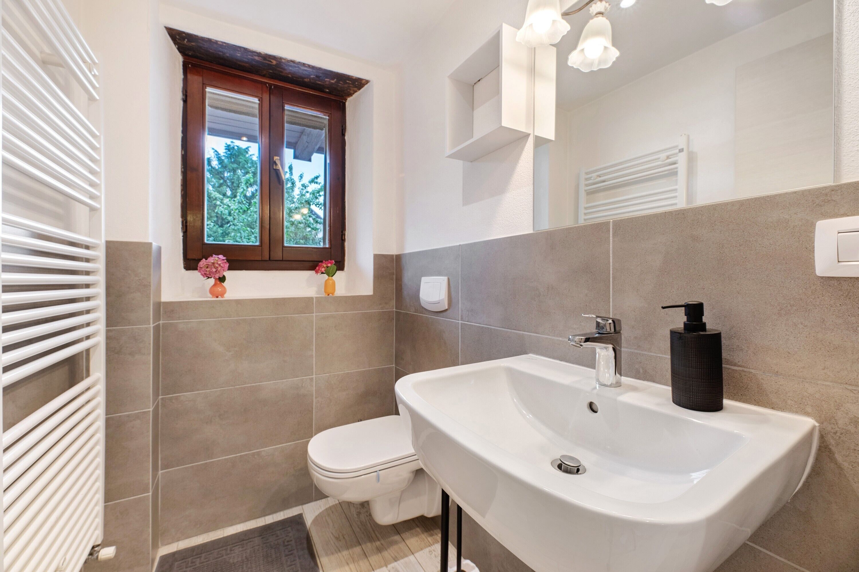 Un baño con lavamanos blanco, una ventana con vistas y un inodoro.