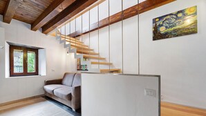 A modern interior with a wooden staircase, a sofa, and a painting on the wall.