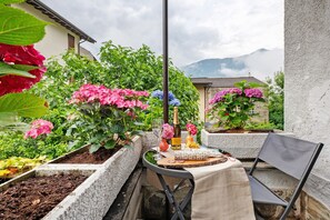 Un balcon avec une table dressée pour un repas, entouré de plantes et de fleurs en pot.