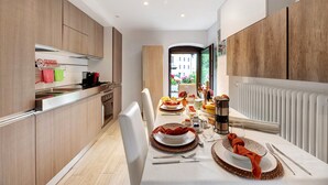 A modern kitchen with wooden cabinets, a dining area with a table set for a meal, and a view of a building outside.