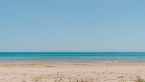A beach with a clear sky and calm sea.