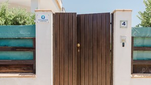 A gated entrance with a wooden door, a sign indicating 'The Pearl of Sicily,' and a number '4' on a wall.