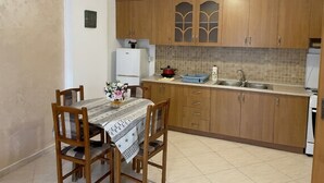 A kitchen with wooden cabinets, a dining table with chairs, a refrigerator, and a sink. - Spacious Sea View Apartment Private Balcony · Steps to Beach · Vlora Albania (Vlore)