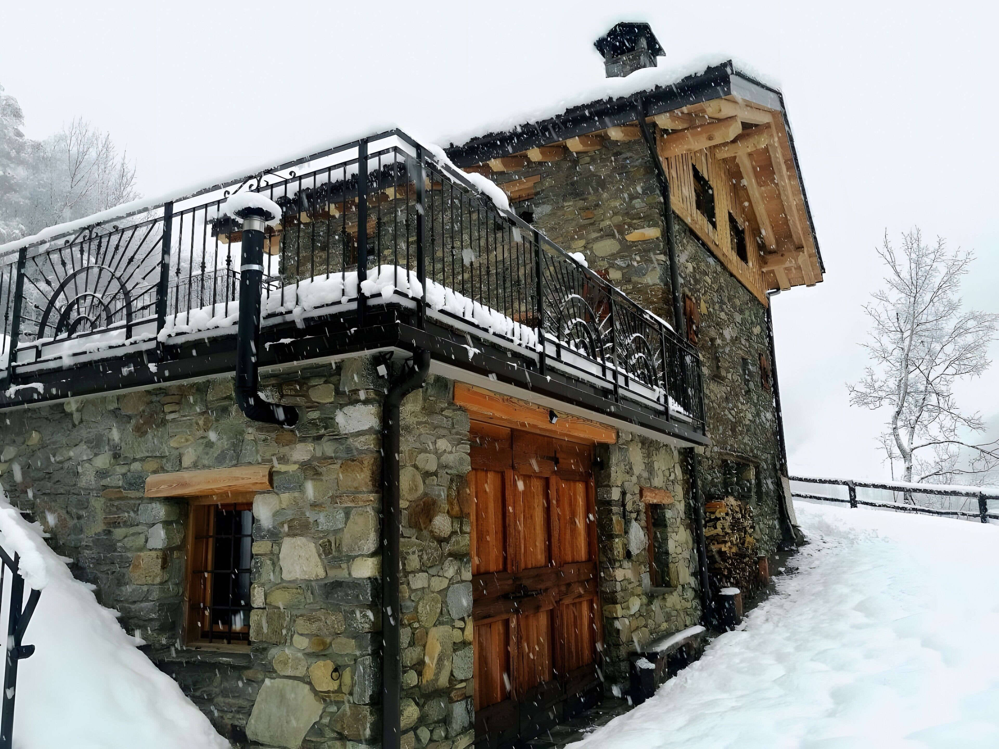 A stone building with a balcony, wooden doors, and a stone staircase.