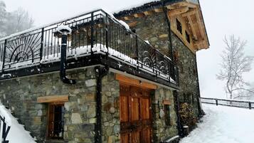 A stone building with a balcony, wooden doors, and a stone staircase.