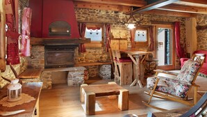 A rustic interior with a stone fireplace, wooden furniture, and a rocking chair. - Deluxe Room "Chalet Cuore Selvatico" with Mountain View, Terrace, and Private Garden (Monno)