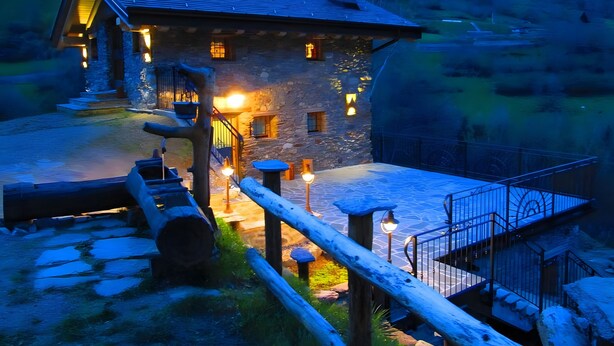 A stone building with a wooden staircase, a stone wall, and a metal fence. - Deluxe Room "Chalet Cuore Selvatico" with Mountain View, Terrace, and Private Garden (Monno)