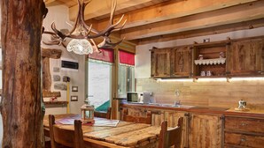 Une cuisine rustique avec des meubles de rangement en bois, une table à manger en bois et un lustre orné de bois de cerf.