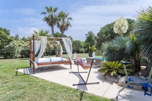 Un jardín con una cama, una hamaca y equipo de ejercicio.