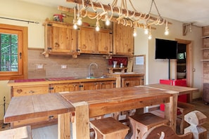 A wooden kitchen with a large island, wooden cabinets, and a hanging light fixture. - Apartment in Chalet 'Open Space Deluxe' with Mountain View and Private Garden (Monno)