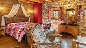 A wooden cabin bedroom with a bed, a chair, a dresser, and a stone wall.