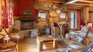 A rustic interior with a stone fireplace, wooden furniture, and a rocking chair.
