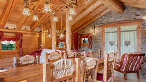 A wooden interior with a high ceiling, stone walls, and a dining area with wooden furniture.