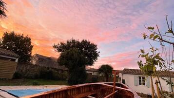 A wooden boat in a backyard with a pool, trees, and a house in the background.