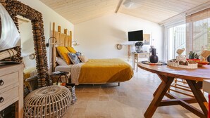 Een kamer met een bed, een houten plafond, een televisie en een raam met jaloezieën.